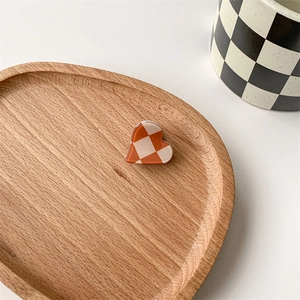 Close-up of heart-shaped checkerboard hair claw clip in orange and white on a wooden tray