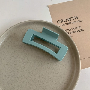 Close-up of a matte Morandi green rectangular hair claw clip on a ceramic tray