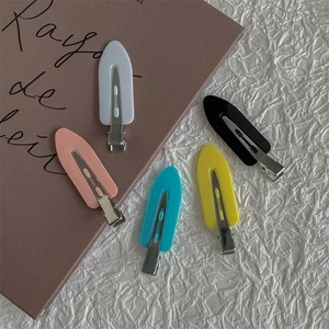 Matte candy-colored duckbill hair clips in five pastel shades on a vintage book
