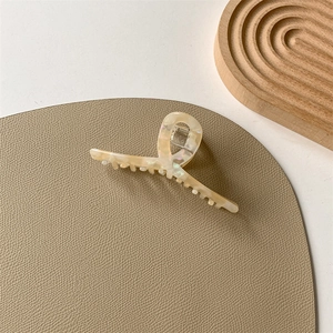 Close-up of elegant cream acetate hair claw clip with pearlescent finish and metal spring