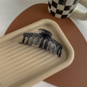 Detail shot of a large grey gradient hair claw clip on a stylish decorative tray