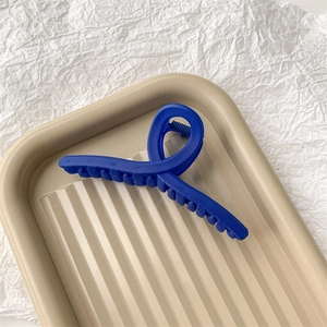 Vue détaillée d'une grande pince à cheveux bleu foncé mat dans un plateau minimaliste