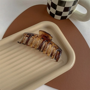 Detail of a large amber tortoiseshell hair claw clip resting on a textured display tray