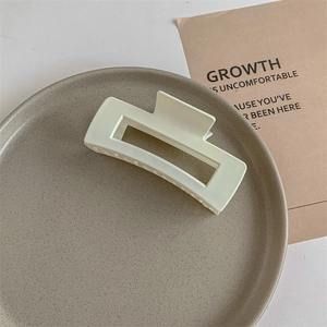 Detailed view of large matte cream rectangular claw clip on a gray ceramic plate