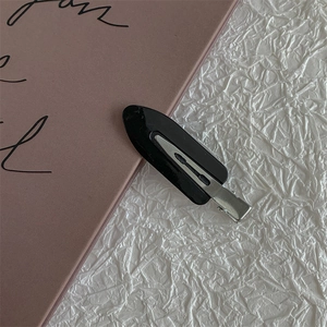 Close-up of black seamless hair clip with shiny plastic finish and silver metal base