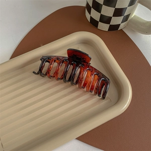 Close-up of amber tortoise shell large shark hair claw clip on a decorative tray