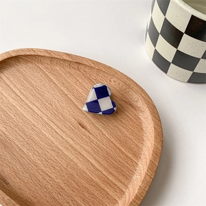 Close-up of heart-shaped blue and white checkered hair clip on a wooden tray