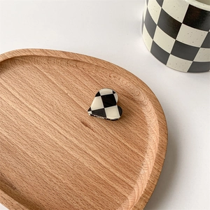 Macro shot of heart-shaped checkerboard hair claw on a wooden tray with a matching mug