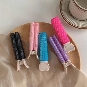 Cinque clip volumizzanti colorate su vassoio in legno per dare volume a radici e frangia