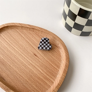 Detail of heart-shaped checkerboard hair claw clip placed on a wooden tray