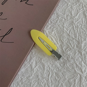 Detail view of a bright yellow matte duckbill hair clip with a silver metal base