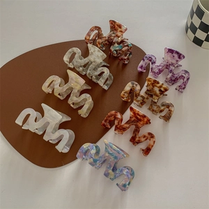 Set of wavy acetate hair claws in marble and tortoiseshell patterns for elegant styling