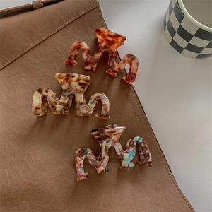 M-shaped wavy acetate claw clips in amber, beige, and floral patterns for women