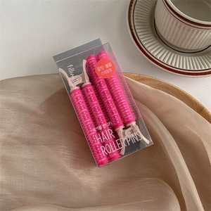 Dettaglio di due bigodini rosa per il volume delle radici in una confezione regalo