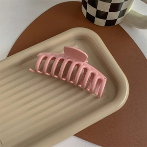 Detail view of pink matte hair claw clip on an elegant aesthetic display tray