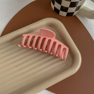 Macro view of a large pink matte hair claw clip on a stylish display tray