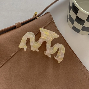 Detailed view of wave-shaped marble texture acetate hair claw clip on soft fabric