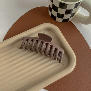 Detail of a large matte hair claw clip on a decorative tray for thick hair styling