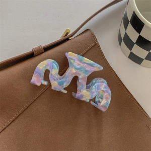 Detail of wave-shaped marble texture acetate hair claw clip on a brown suede background