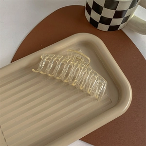 Detailed view of a transparent yellow shark hair claw clip on a decorative tray