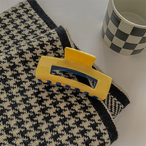 Detail of large acetate hair claw clip showing yellow and blue color contrast and smooth texture