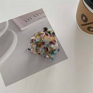 Detailed macro view of colorful terrazzo pattern hair clip on minimalist grey background