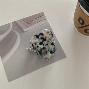 Detail of a minimalist marble texture hair claw clip with black and white patterns
