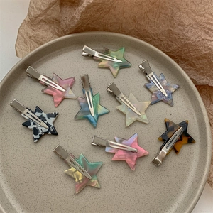 Star shaped acetate hair clips in multiple colors displayed on a ceramic tray