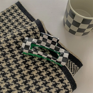 Detail of checkered rectangular hair claw clip with vibrant green interior lining