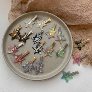 Star shaped acetate hair clips in colorful marble patterns on a ceramic tray
