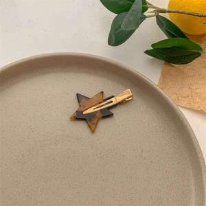 Detailed view of a star-shaped tortoiseshell hair clip on a minimalist display tray