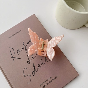 Detail of pink butterfly hair claw with pearlescent acetate texture on a book cover