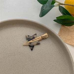 Detailed view of star-shaped acetate hair clip with tortoiseshell pattern on ceramic tray