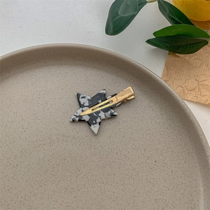 Star-shaped acetic acid hair clip with marble pattern on a ceramic aesthetic tray