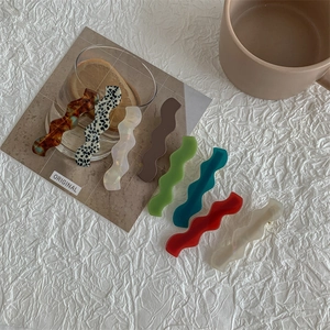 Set of seven wavy acetate hair clips in leopard print and matte colors on a white background