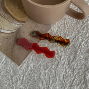 Detail of red and amber tortoiseshell wave hair clips with gold metal snap closures