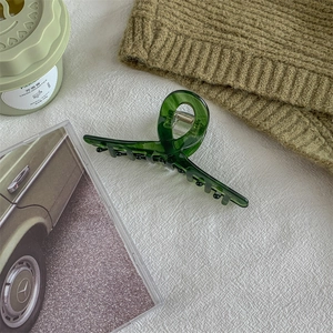 Detailed view of dark green acetate hair claw clip with white Handmade lettering
