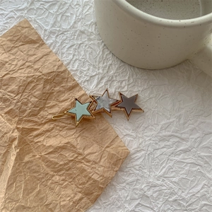 Detailansicht der goldenen Haarspange mit drei farbigen Acetat-Sternen auf Kraftpapier