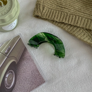 Detail of dark green marble acetate hair claw clip with golden Handmade logo lettering