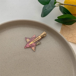 Star shaped acetic acid hair clip in pink tortoise pattern on a ceramic tray