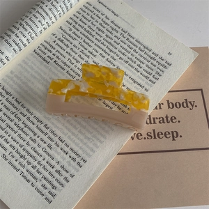Detail of Korean style marbled amber and beige acetate hair claw clip on book