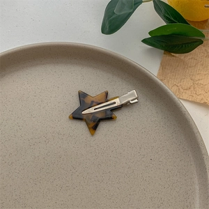Close-up of tortoise shell acetate star hair clip with silver metal alligator grip