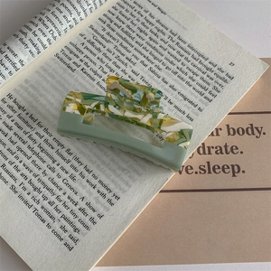 Detail of Korean style marble acetate hair claw clip on vintage book background