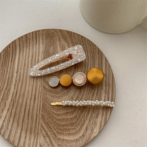 Détail de trois barrettes avec perles et acrylique sur un plateau en bois rustique