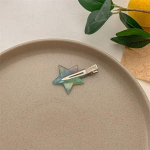 Star-shaped iridescent cellulose acetate hair clip on a minimalist ceramic plate