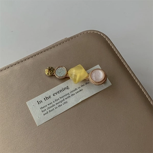 Macro detail of geometric pearl hair clip with gold metal base on leather surface