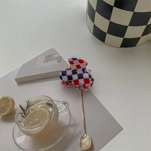 Close-up of tricolor checkered hair claw clip next to a Paris book and lemon tea