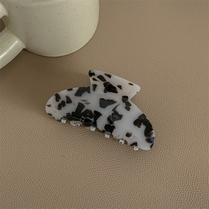 Detail of large acetate hair claw with grey marble pattern on leather surface