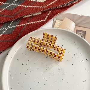 Detail of checkered rectangular hair claw clip in yellow and brown acetate finish