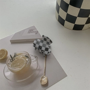 Detailed view of mini checkered hair claw clip on minimalist lifestyle tabletop